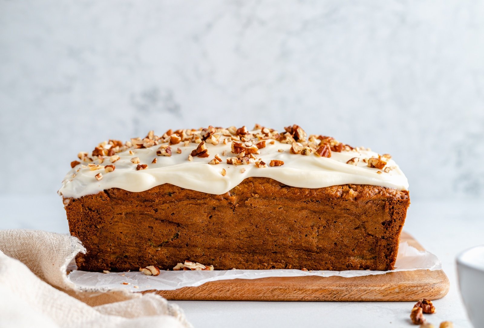 zucchini apple bread with glaze on a cutting board