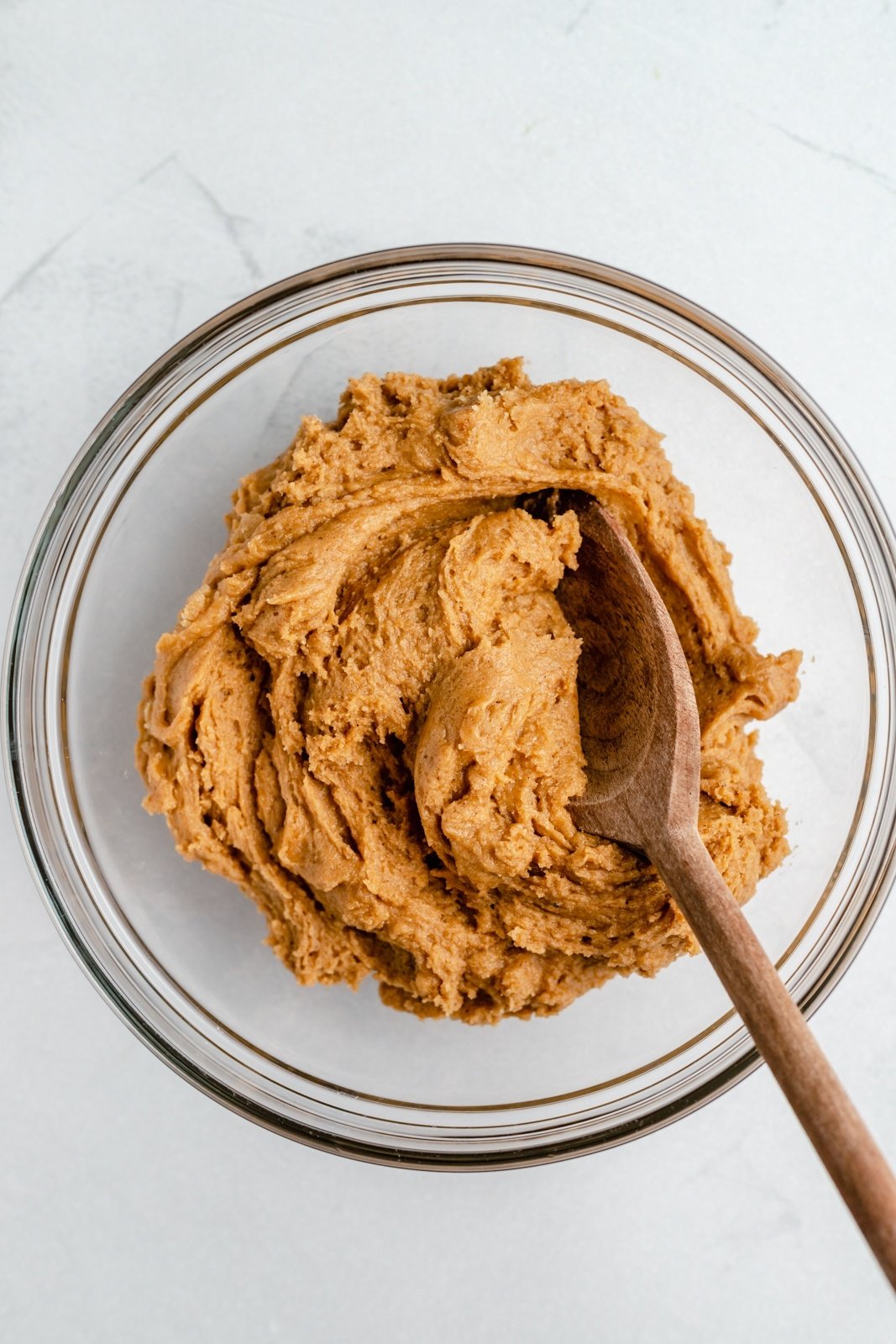 pumpkin snickerdoodle dough in a mixing bowl with a wooden spoon