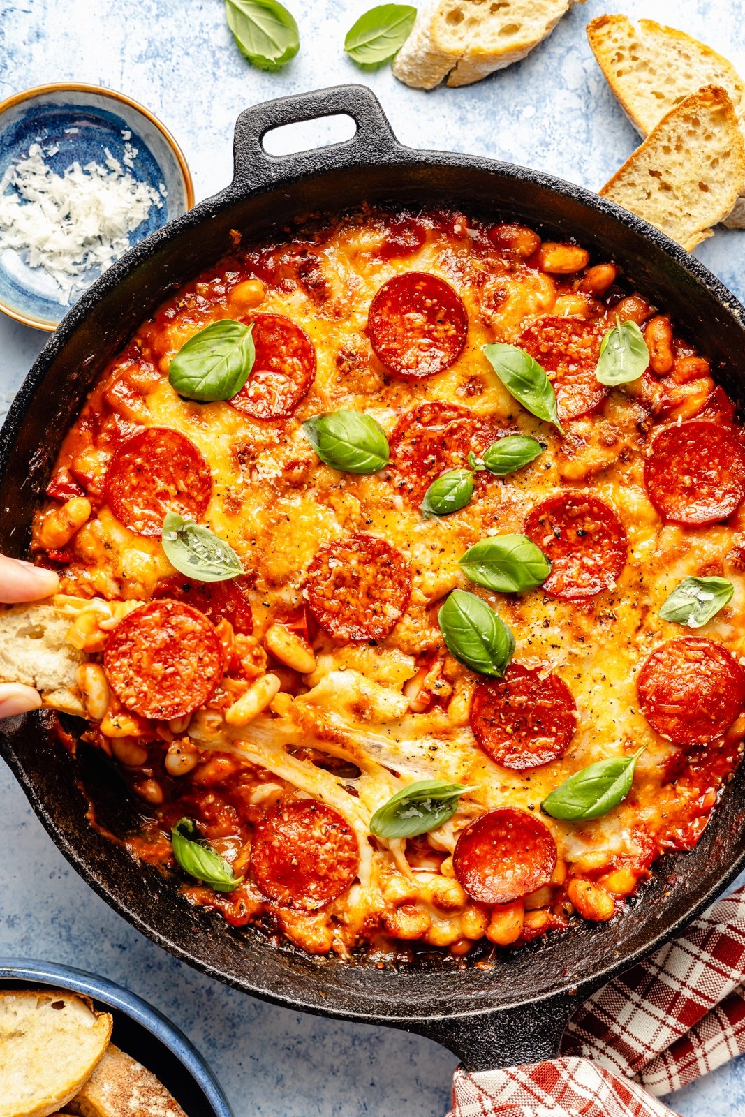 scooping pepperoni white bean dip out of a skillet