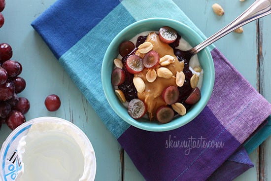 Peanut butter, grape jam, peanuts, and fresh red grapes on top of a bowl of yogurt... who needs the bread!