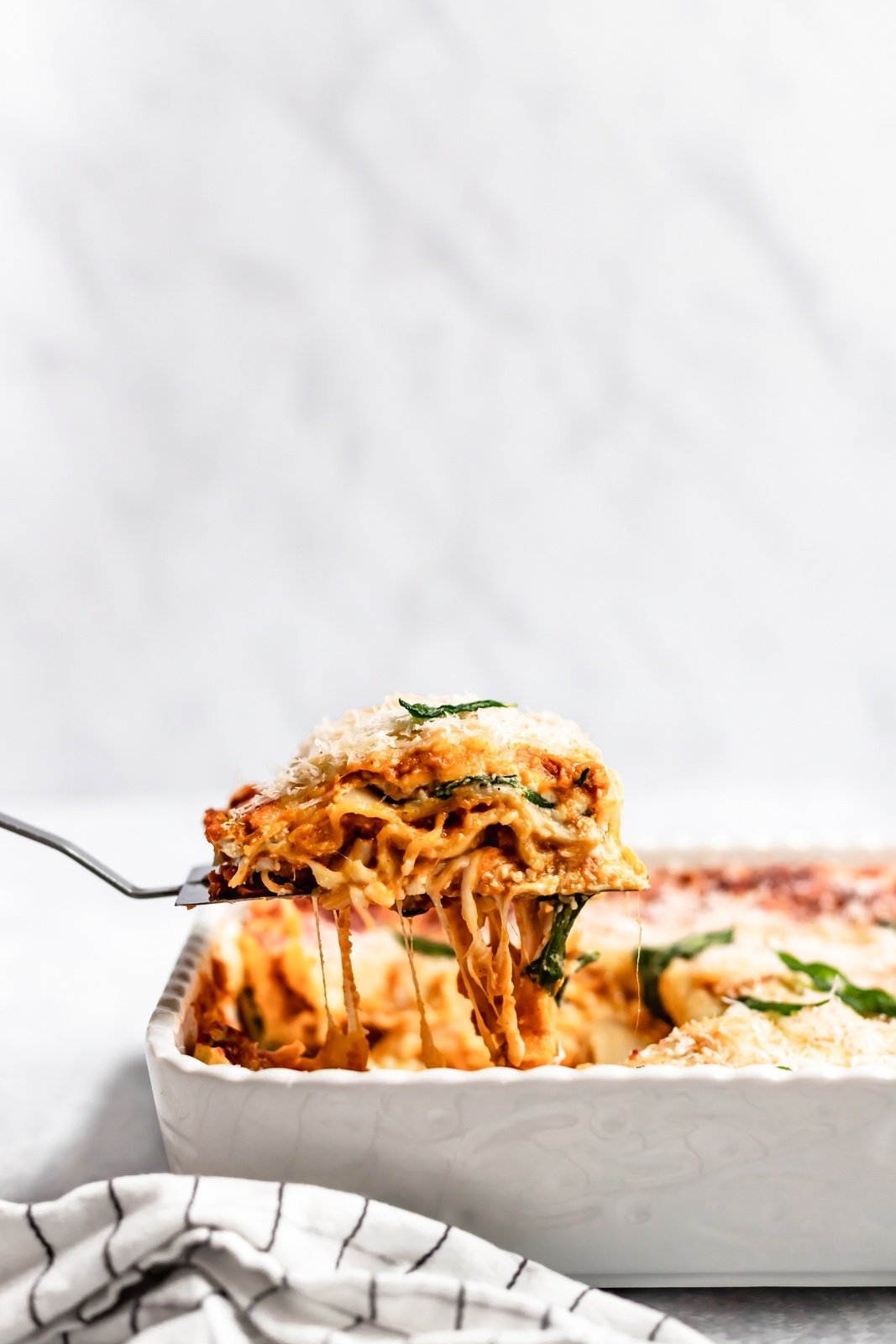 lifting a slice of vegetarian pumpkin lasagna out of a pan