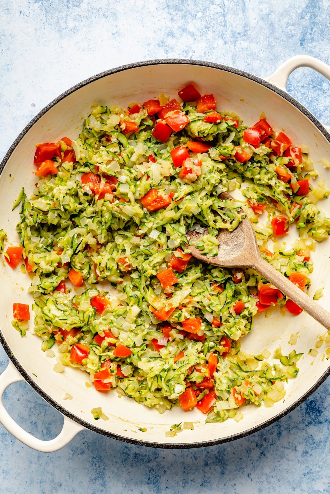 cooking zucchini and tomatoes in a pan to make a zucchini sausage baked orzo