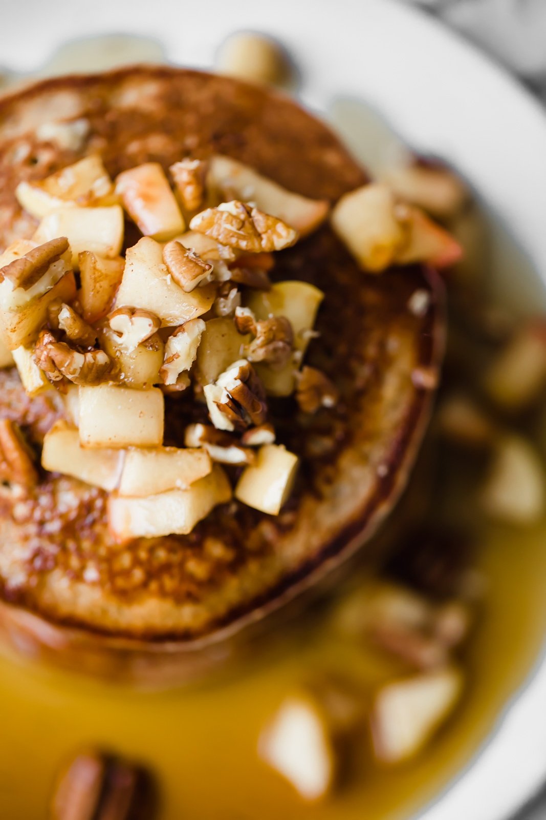 overhead shot of healthy apple pancakes topped with apples and pecans