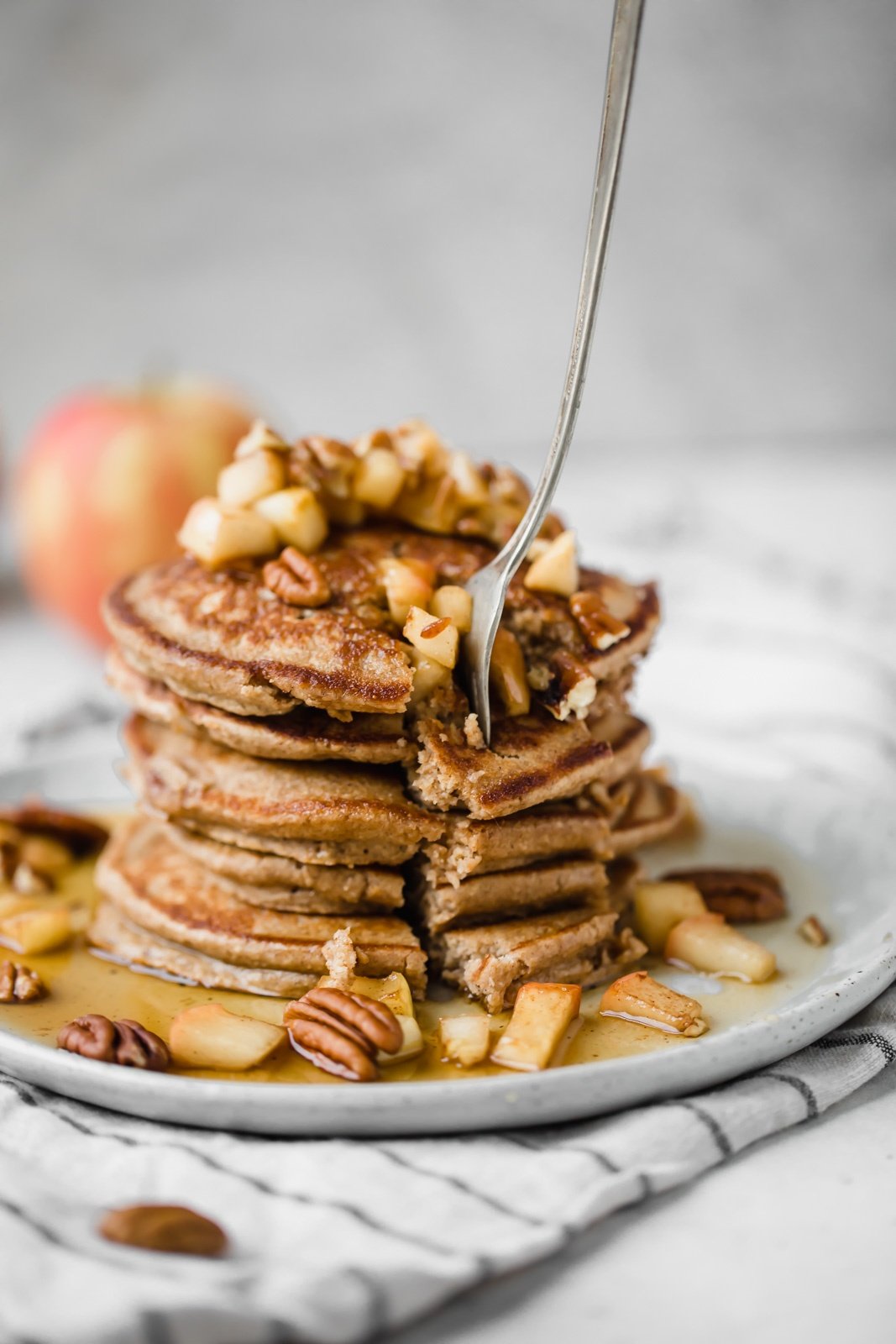 healthy apple pancakes on a plate with a fork removing pancakes