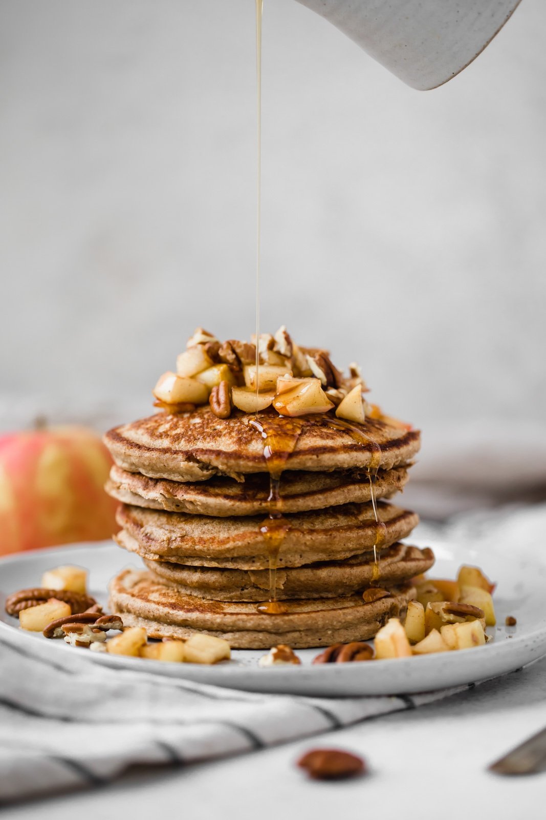 healthy apple pancakes with maple syrup being poured on top