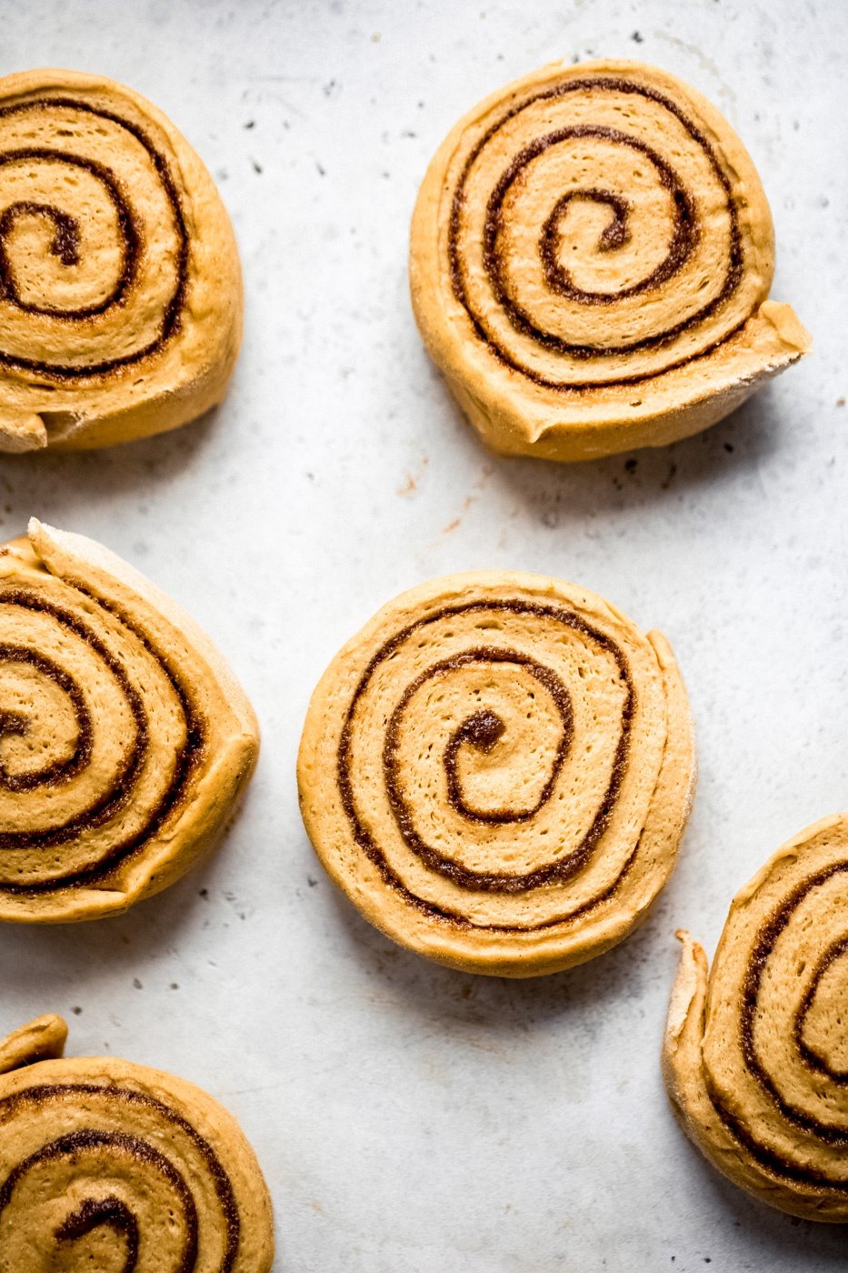 pumpkin cinnamon rolls rounds on surface pre-bake