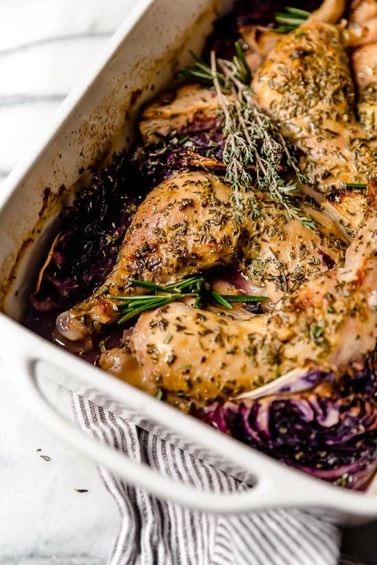 Cider-marinated chicken, red cabbage and apples in a baking dish.