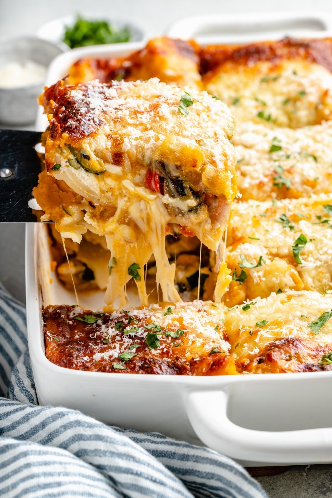 pulling up a slice of butternut squash lasagna from a pan