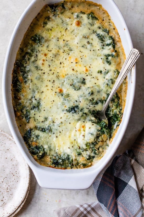 Spinach Gratin in a casserole dish with a serving spoon.