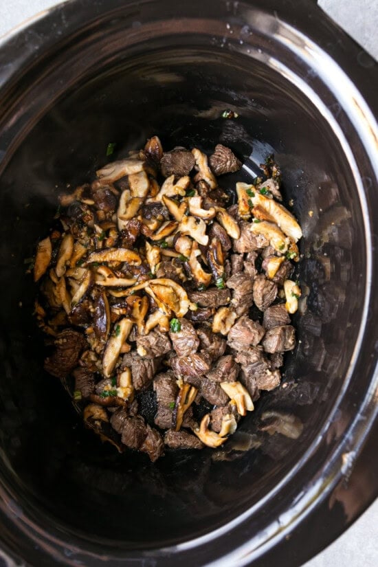 Add mushrooms to the crock pot with beef.