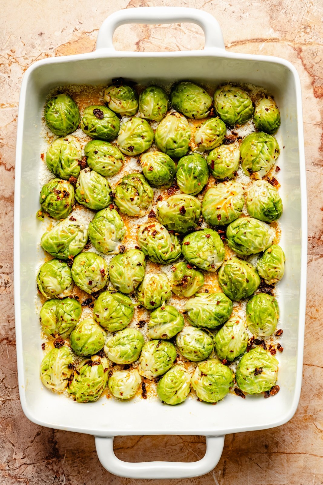 spicy roasted brussels sprouts in a pan over a layer of parmesan cheese