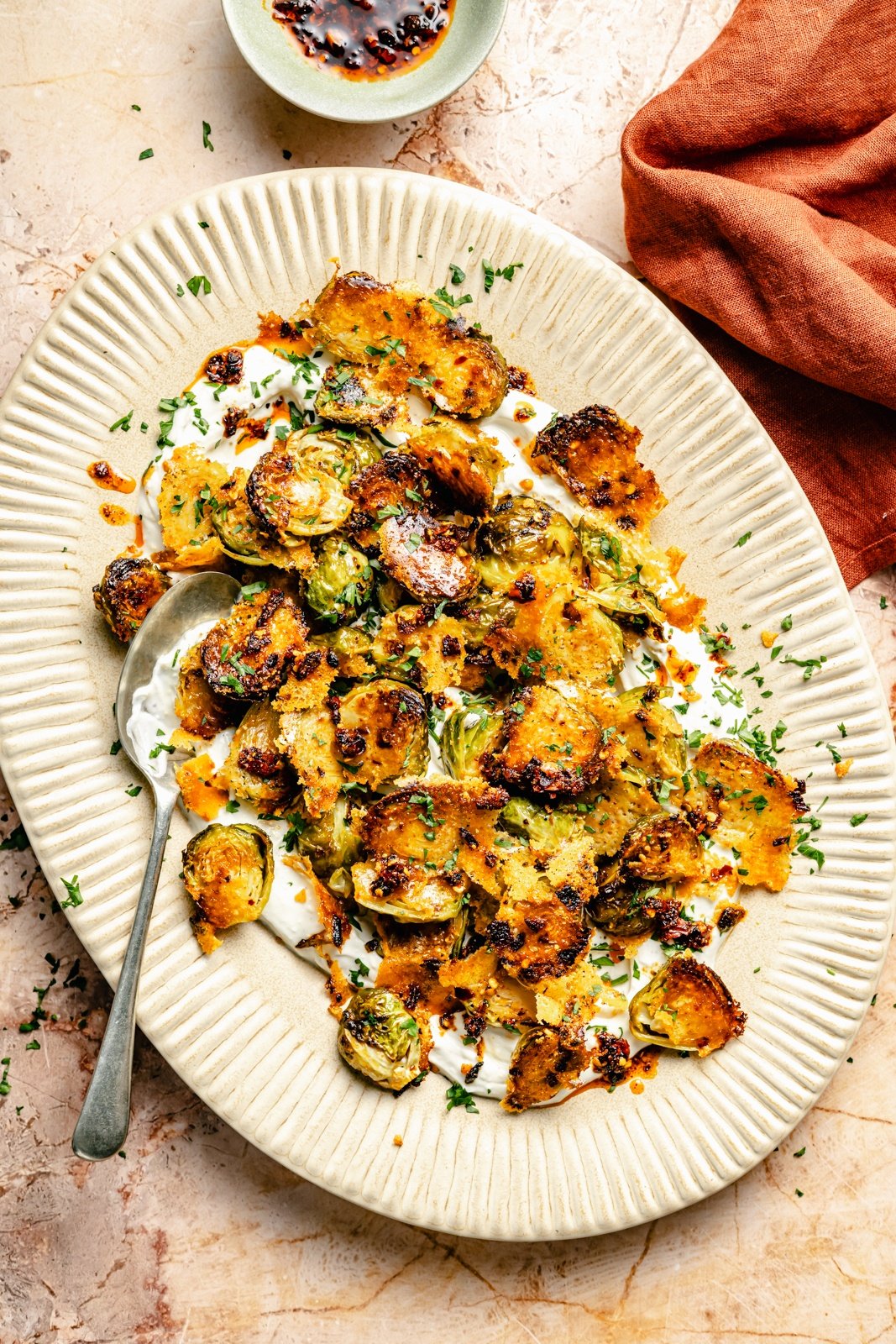 spicy roasted brussels sprouts with parmesan and yogurt sauce on a platter