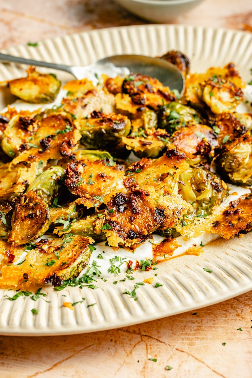 spicy parmesan roasted brussels sprouts on a platter with yogurt sauce