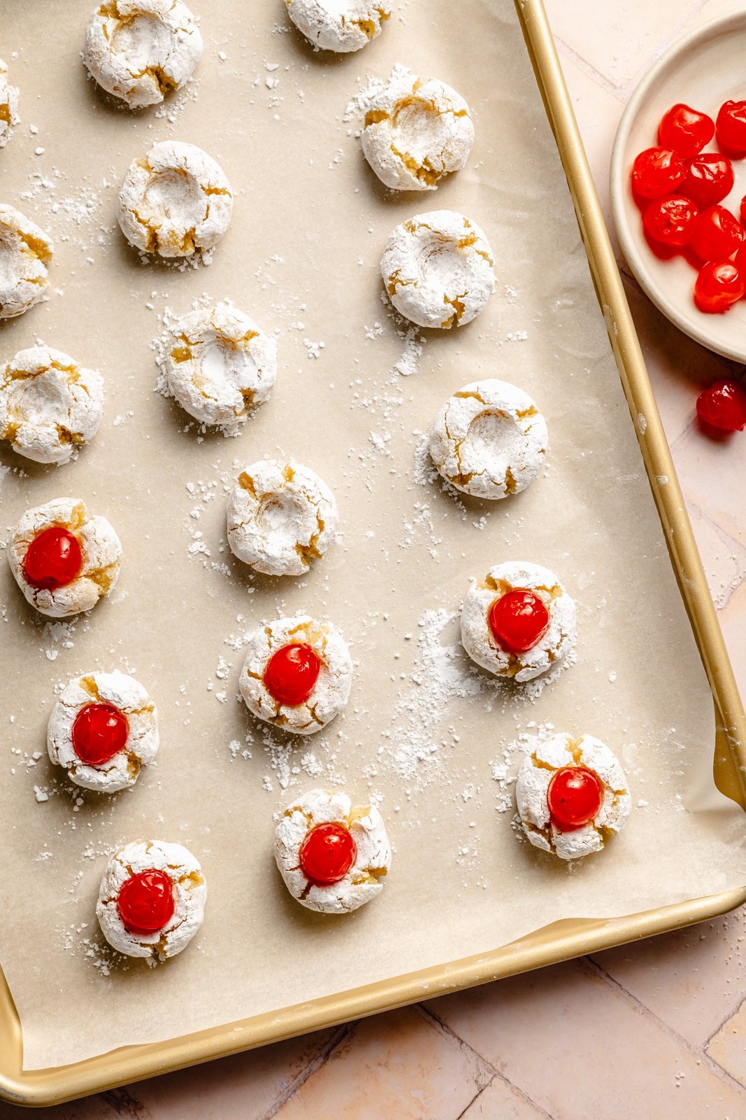 cherry almond cookies on a baking sheet topped with maraschino cherries