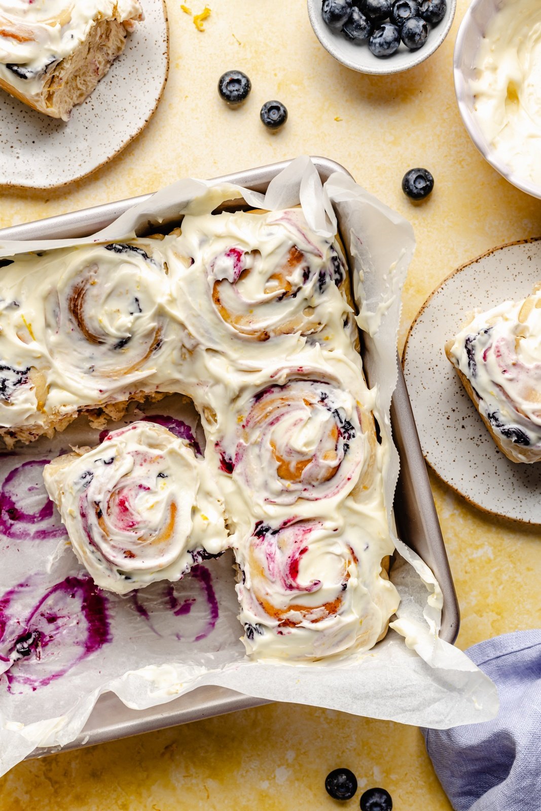 lemon blueberry sweet rolls with lemon frosting in a square pan