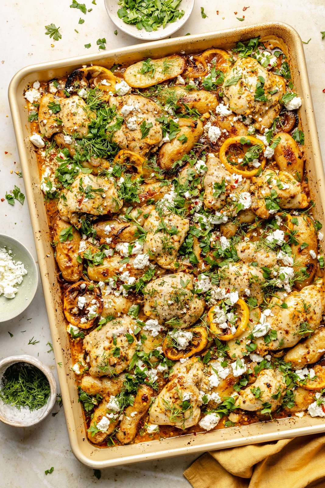 sheet pan lemon chicken and potatoes toped with herbs and feta
