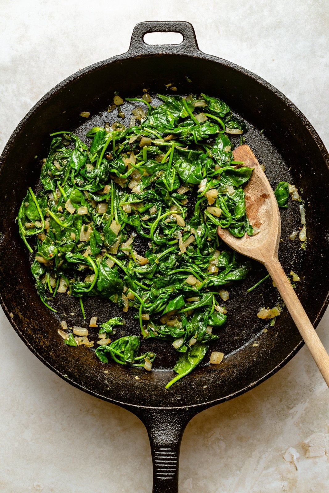 cooking spinach in a pan to make spinach artichoke dip