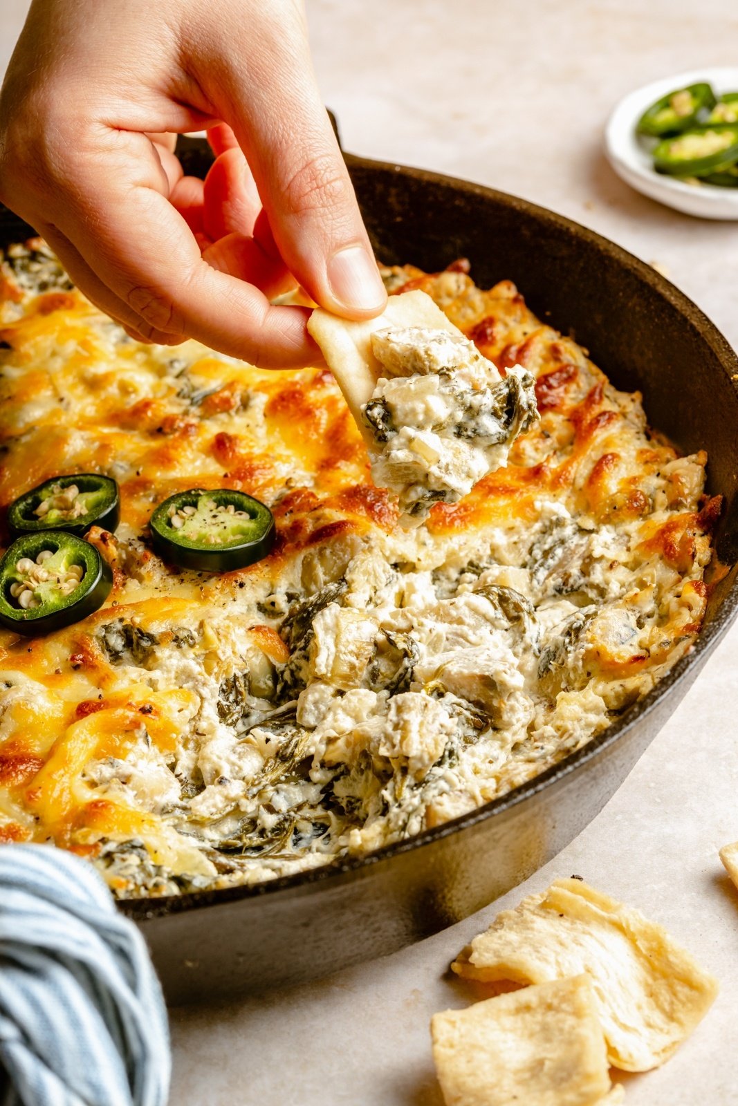 dipping a chip into jalapeño spinach artichoke dip