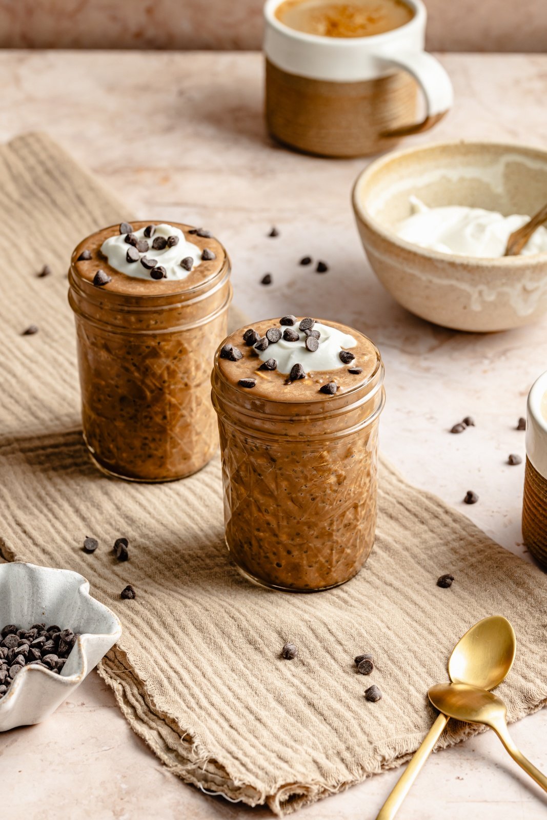 two jars of protein coffee overnight oats topped with yogurt and chocolate chips