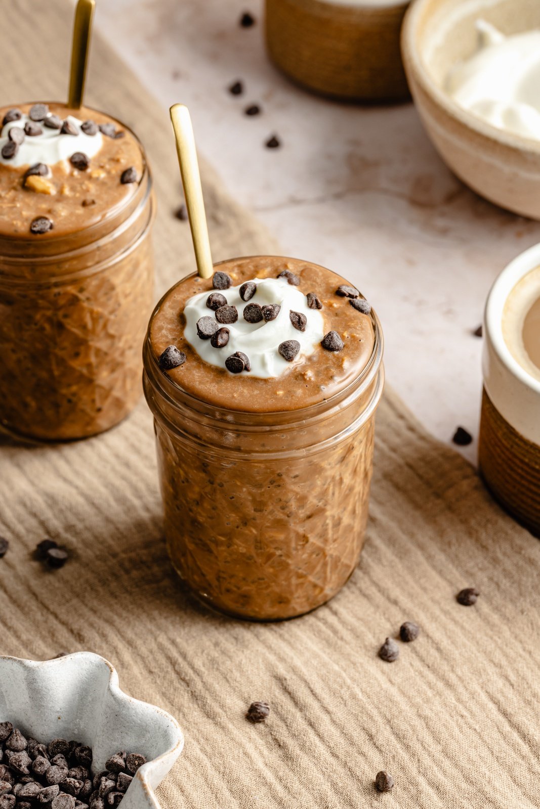 coffee overnight oats in two jars topped with yogurt and chocolate chips