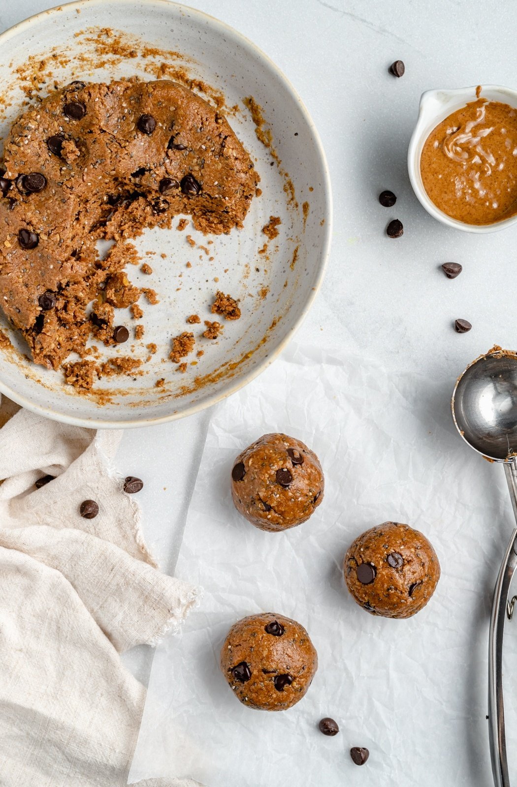 healthy energy bites on parchment paper next to a bowl of mix