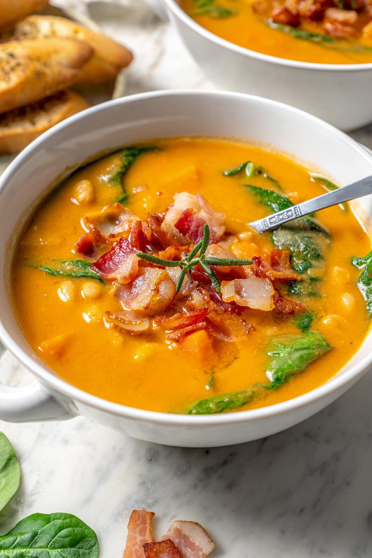 This delicious, hearty navy bean soup is inexpensive and easy to make! Cook it on the stovetop, or in your Instant Pot or slow cooker. Navy bean soup in bowl with bacon on top