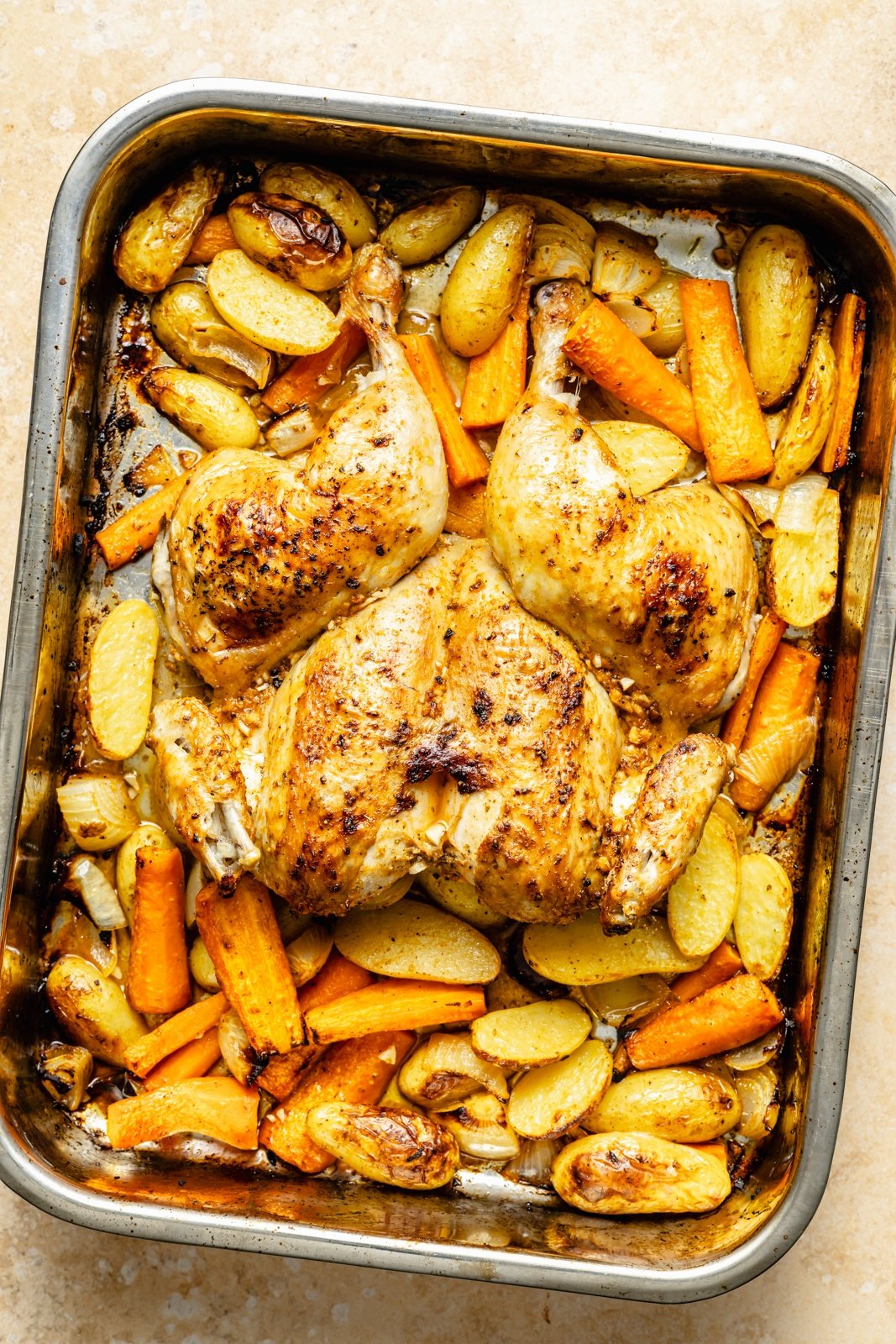 whole roasted chicken and veggies in a roasting pan