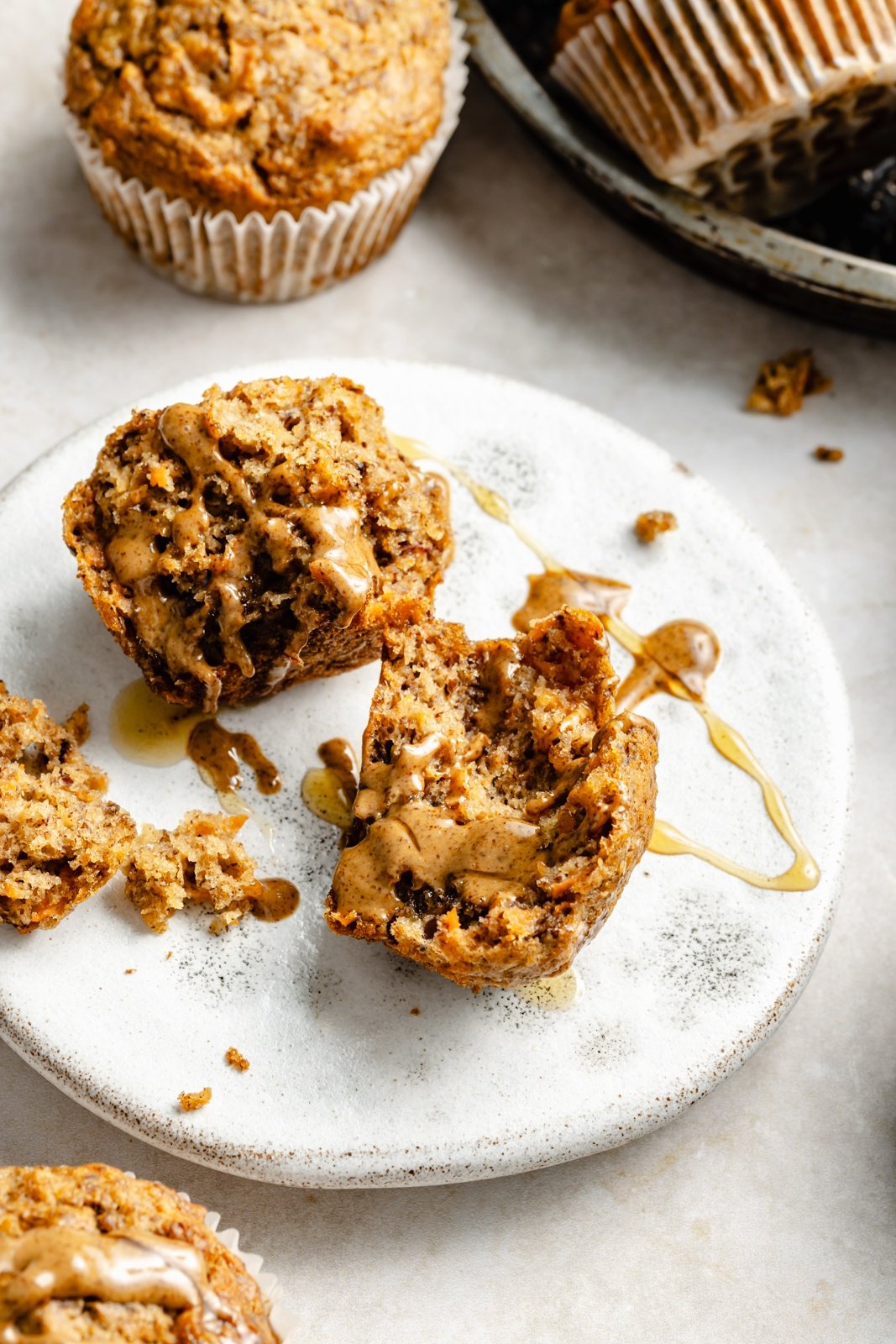 apple, banana, and carrot muffin split in half on a plate