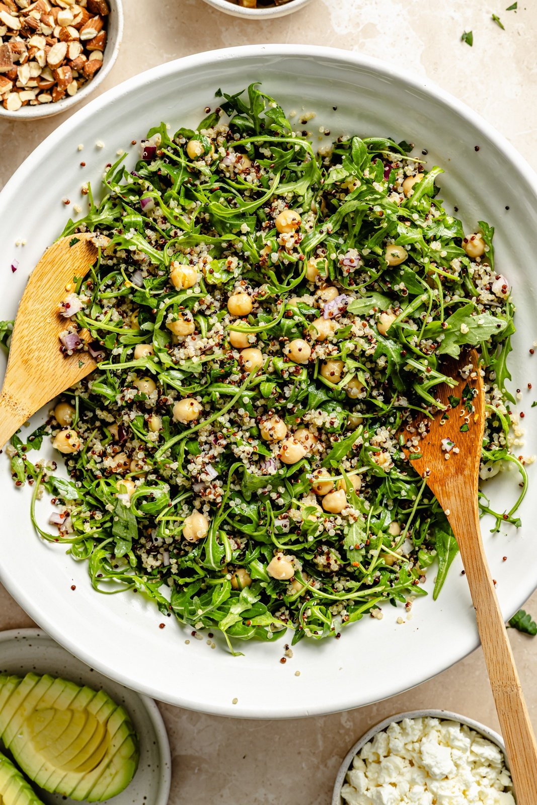 tossing an arugula quinoa salad with chickpeas in a bowl