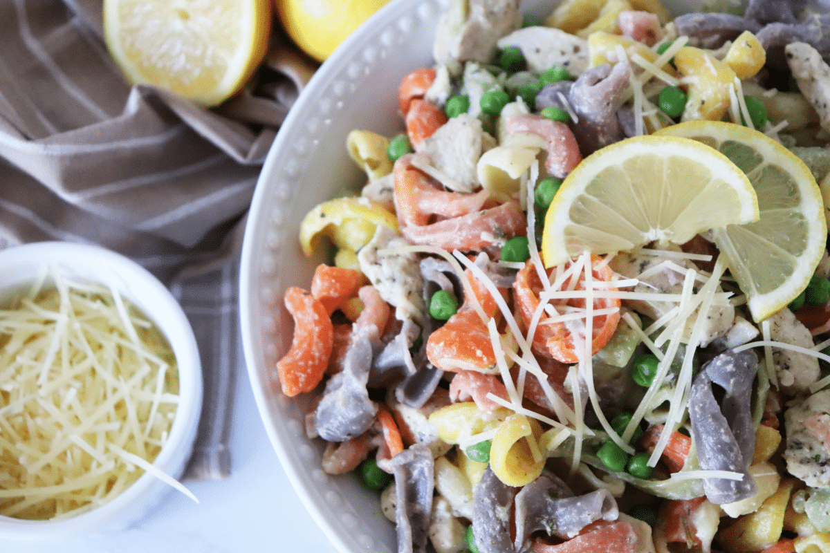 Chicken Pasta with Chicken in a white serving bowl with shredded parmesan and a lemon in the background