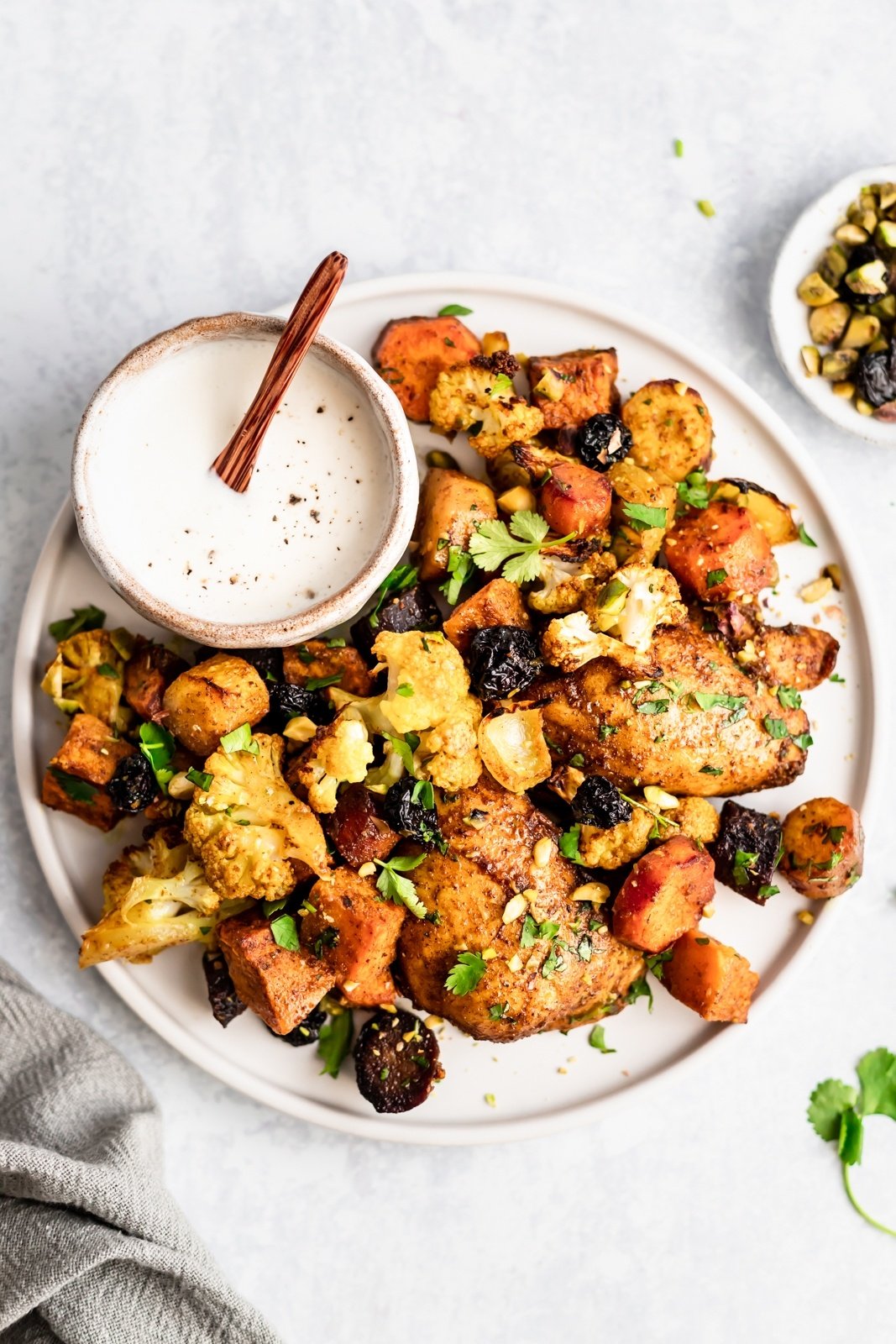 chicken and vegetables on a plate with a bowl of sauce