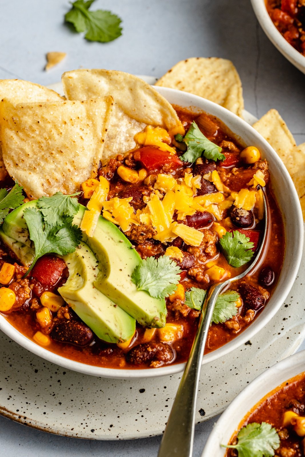 healthy turkey chili in a bowl topped with avocado and tortilla chips