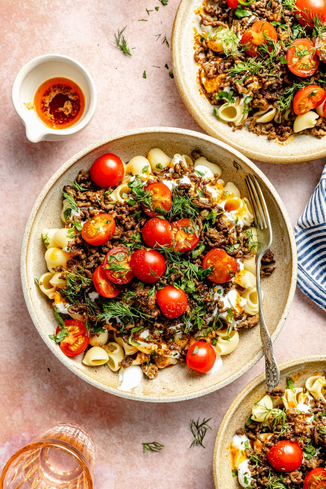 viral Turkish pasta topped with tomatoes and herbs in a bowl