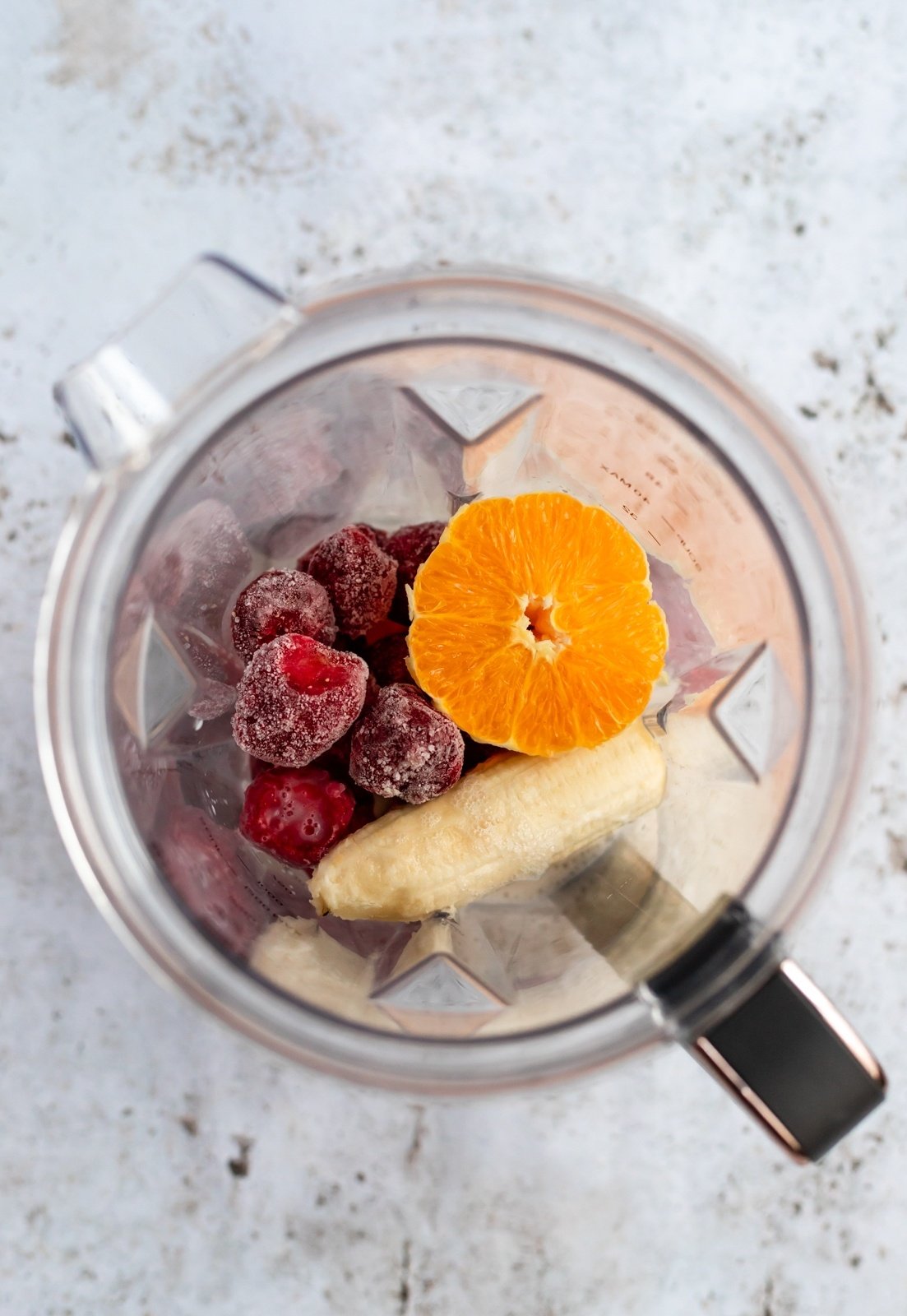banana, strawberries and an orange in a blender