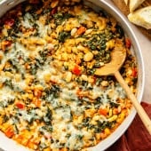 chicken sausage white bean bake in a skillet with a wooden spoon