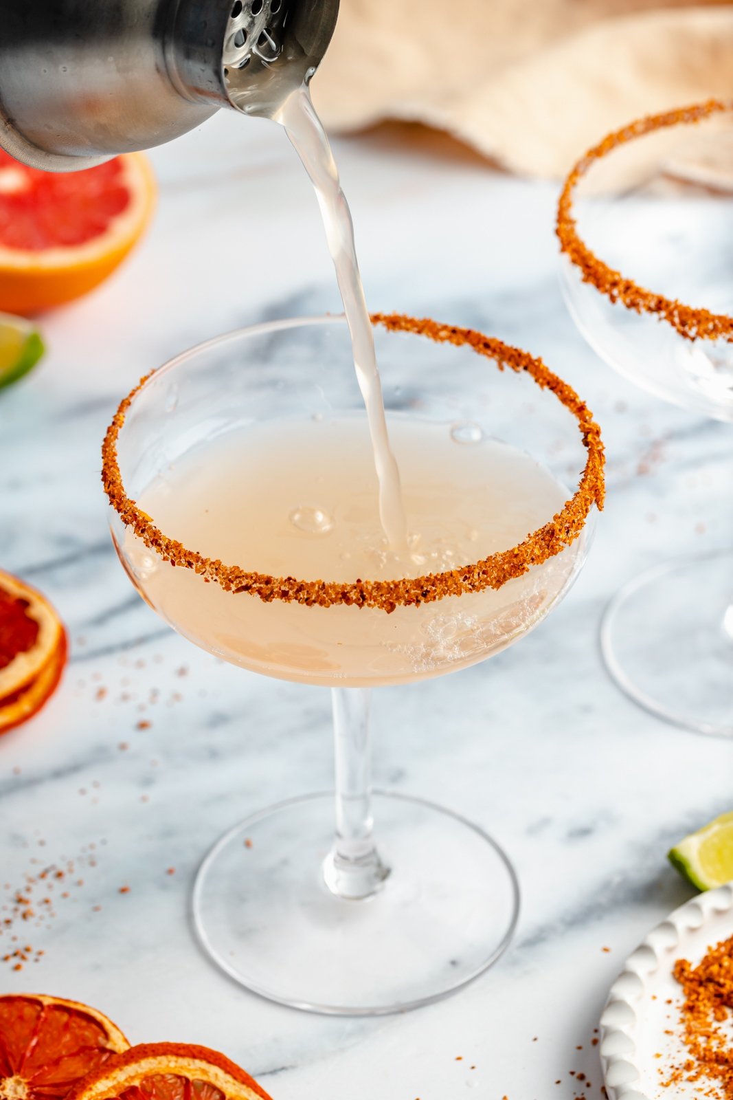 pouring a grapefruit margarita into a cocktail glass