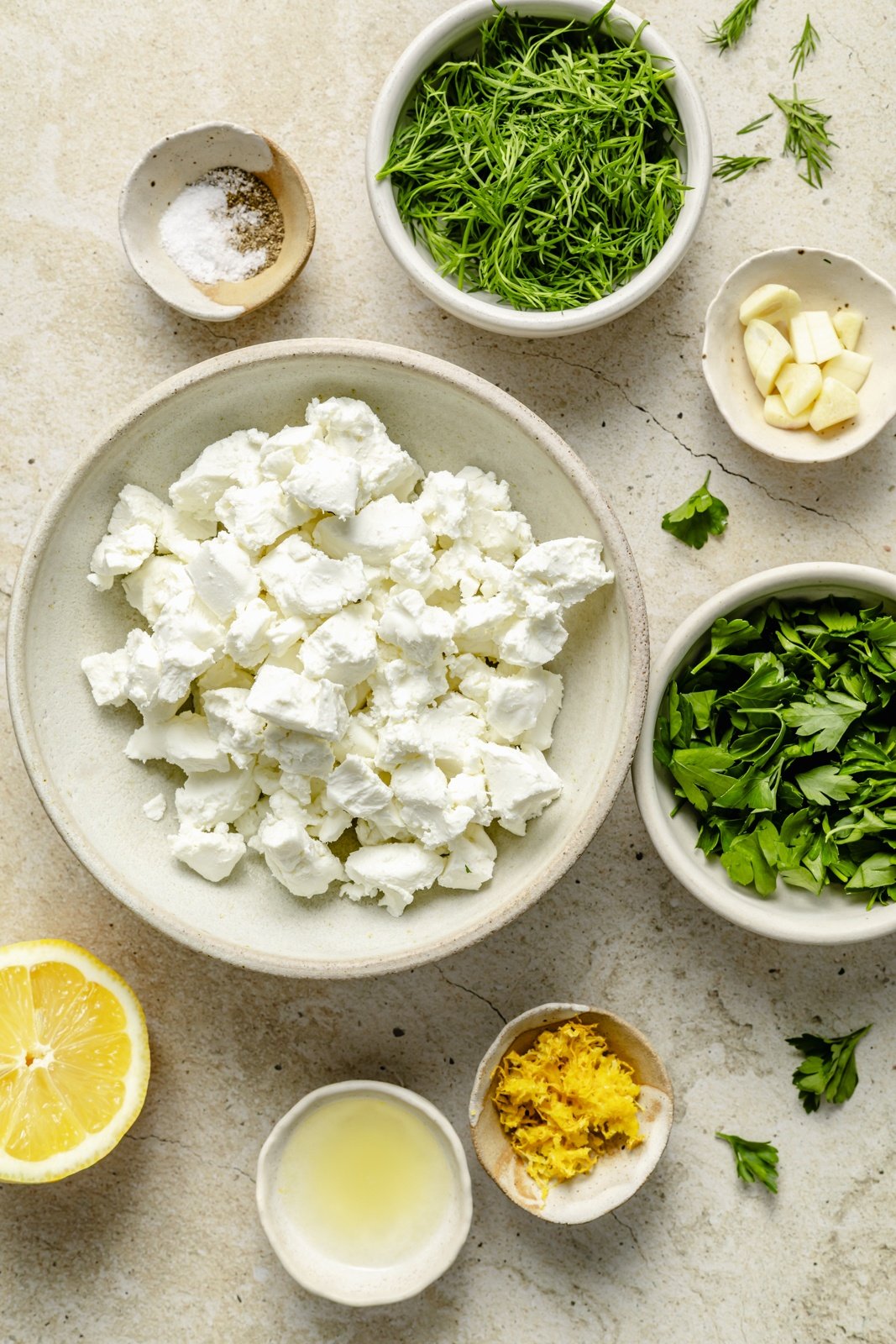ingredients for an herbed goat cheese dip in separate bowls