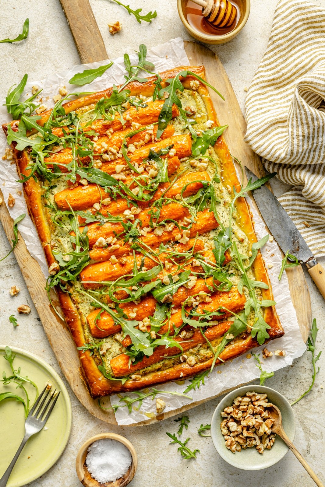 roasted carrot tart topped with arugula on a cutting board