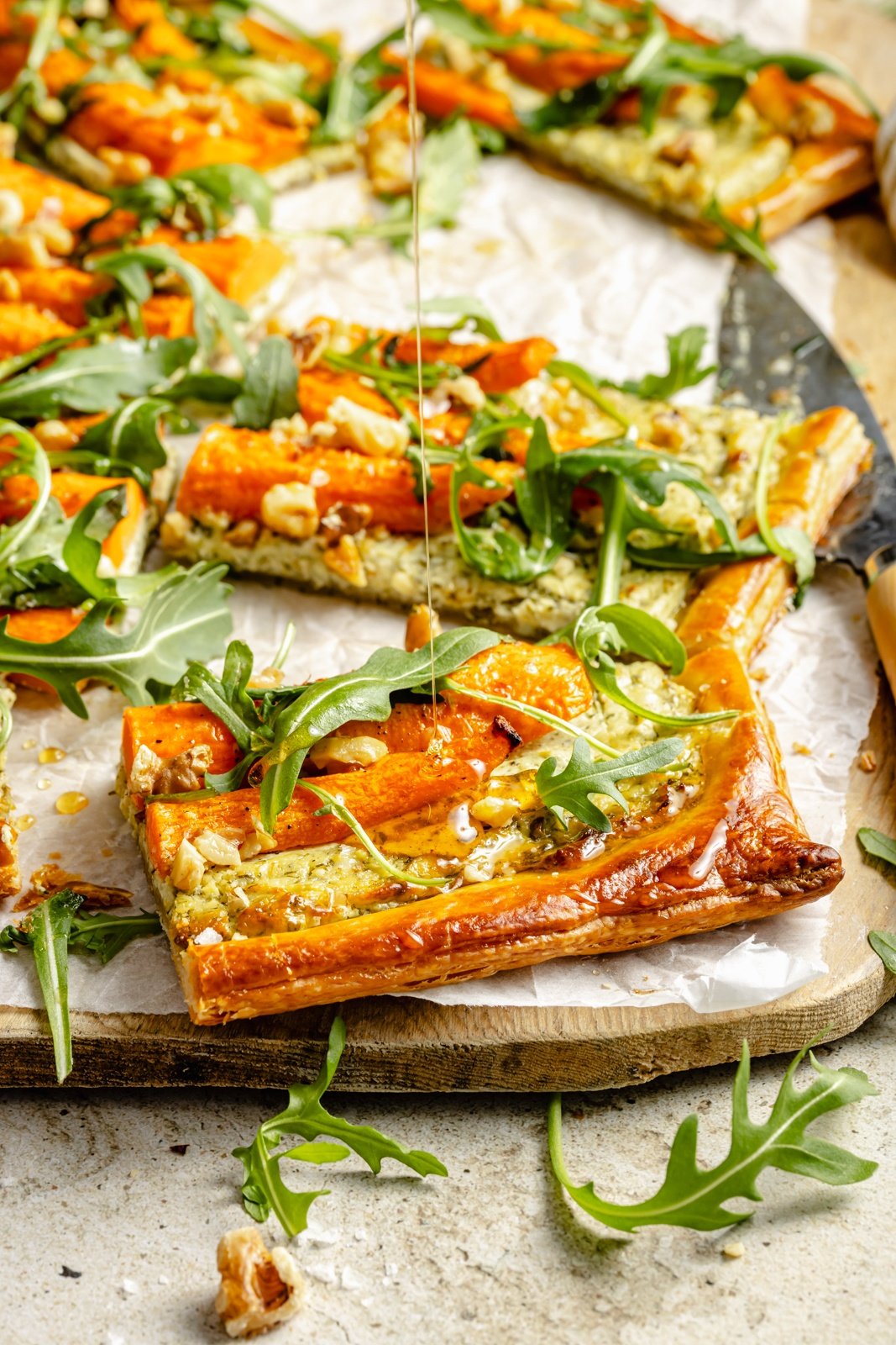 drizzling hot honey onto slices of a roasted carrot tart