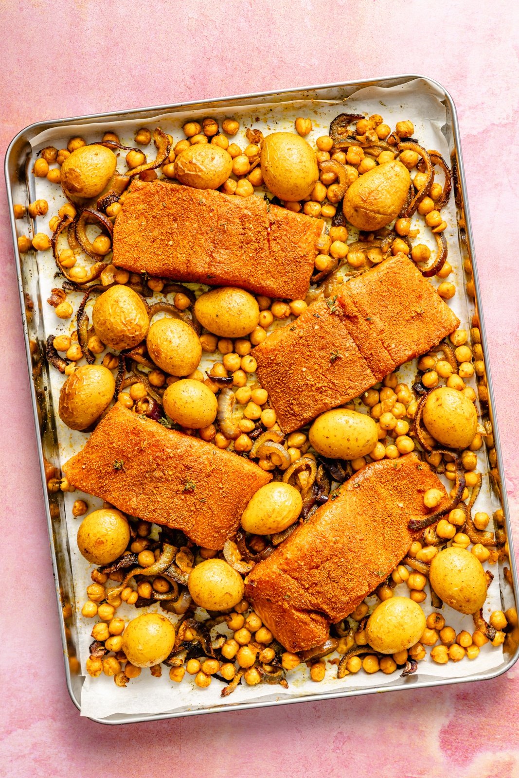 unbaked sheet pan salmon recipe on a pink board