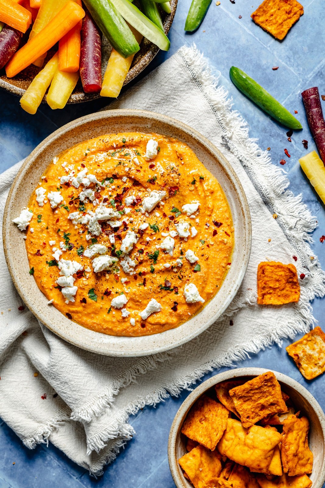 roasted red pepper dip in a bowl next to bowls of carrots and pita chips