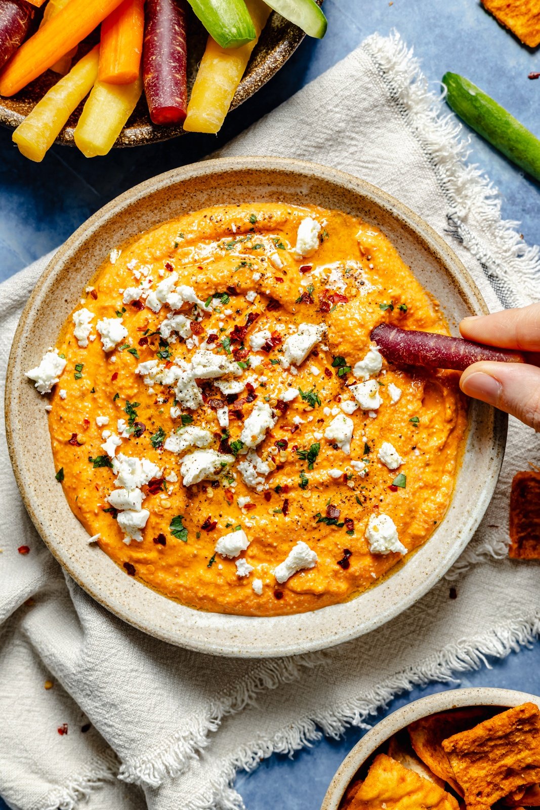 dipping a carrot into roasted red pepper dip