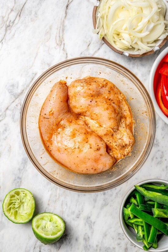 Overhead view of 2 chicken breasts marinating in bowl