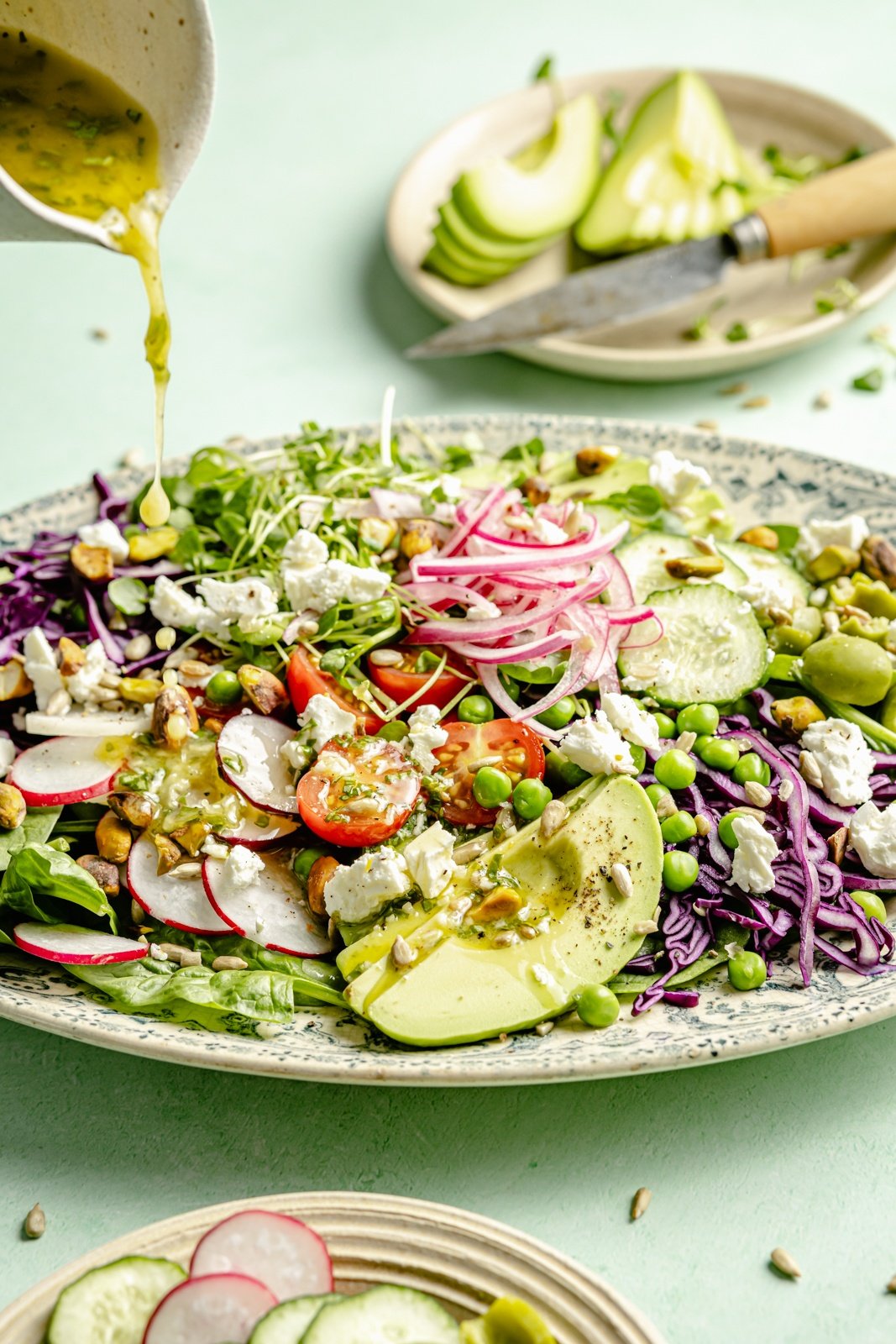 pouring dressing onto a platter with a spring green salad