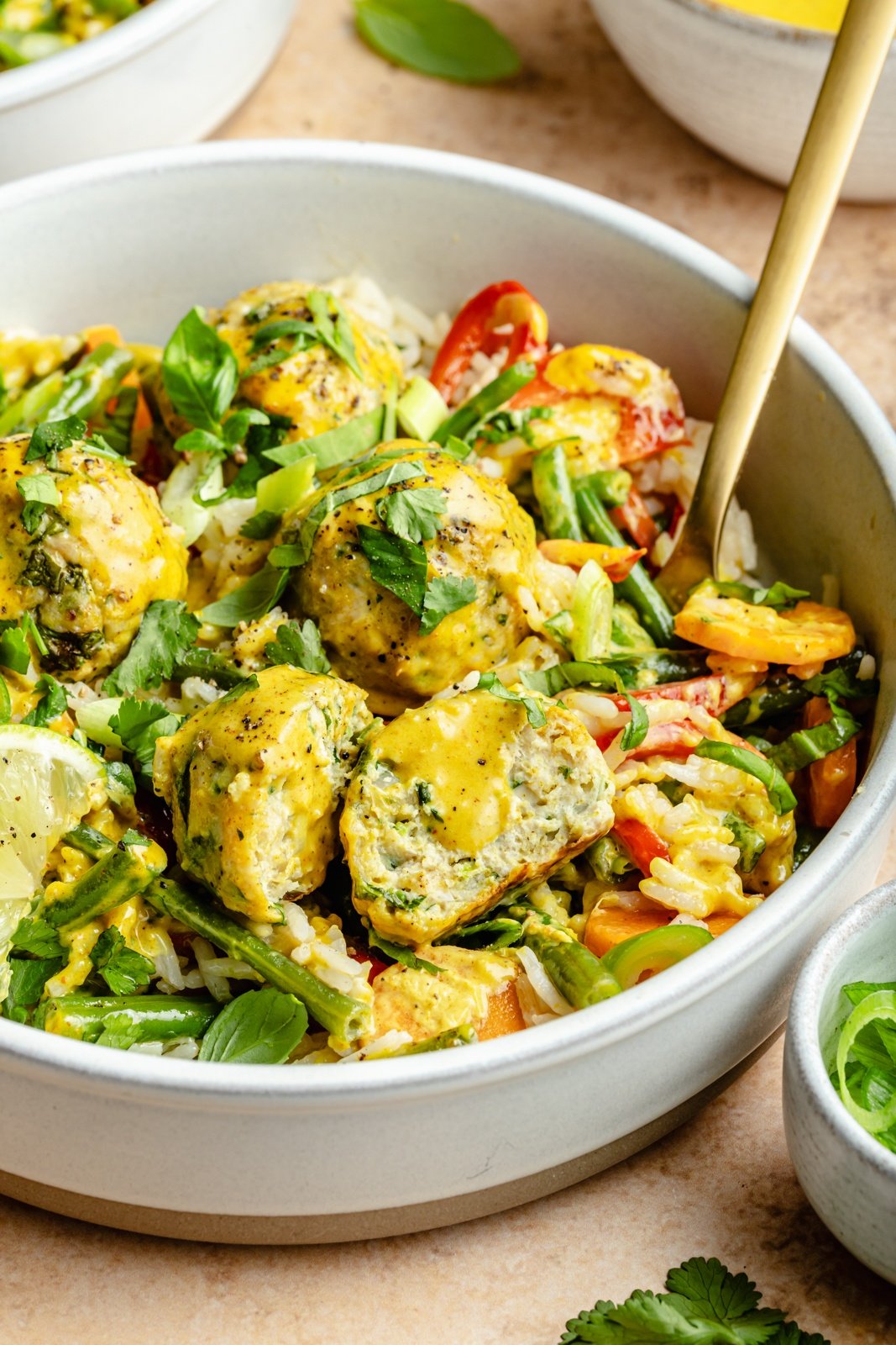 yellow curry chicken meatballs in a bowl with coconut rice and vegetables