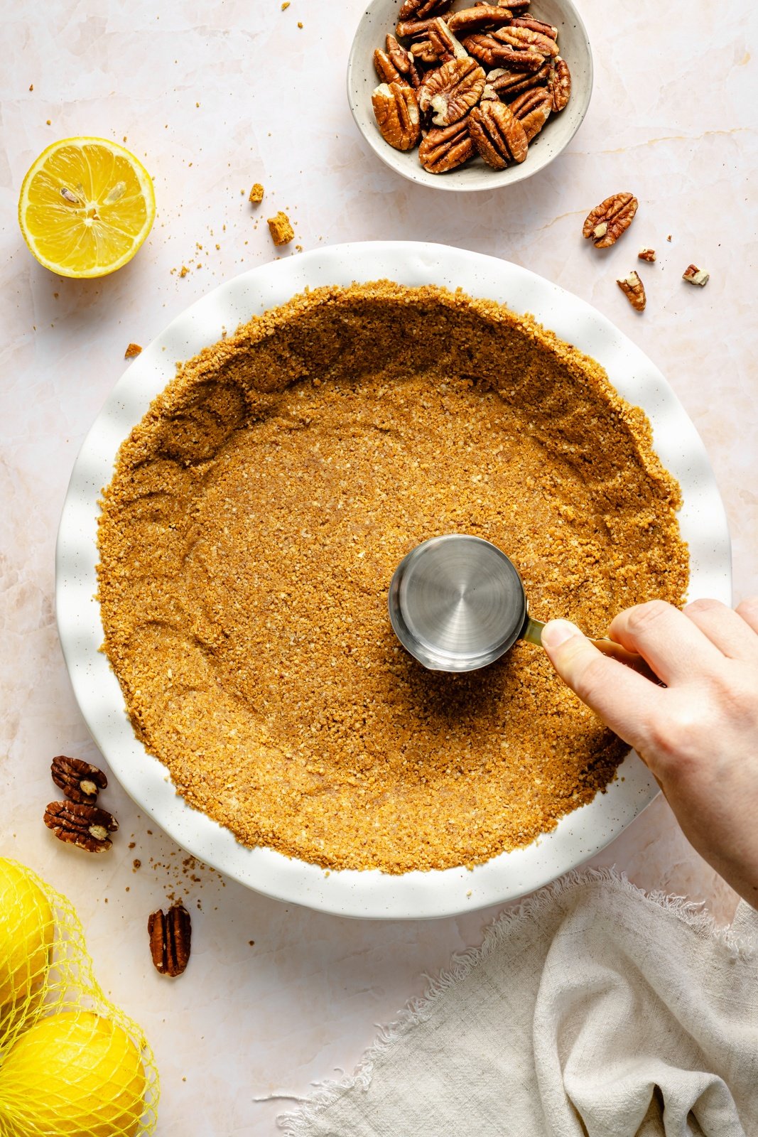 pressing gingersnap crust into a pie pan for lemon cream pie