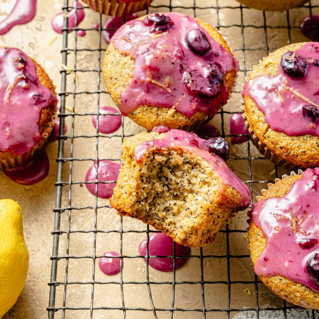 lemon poppy seed muffins with blueberry glaze on a wire rack
