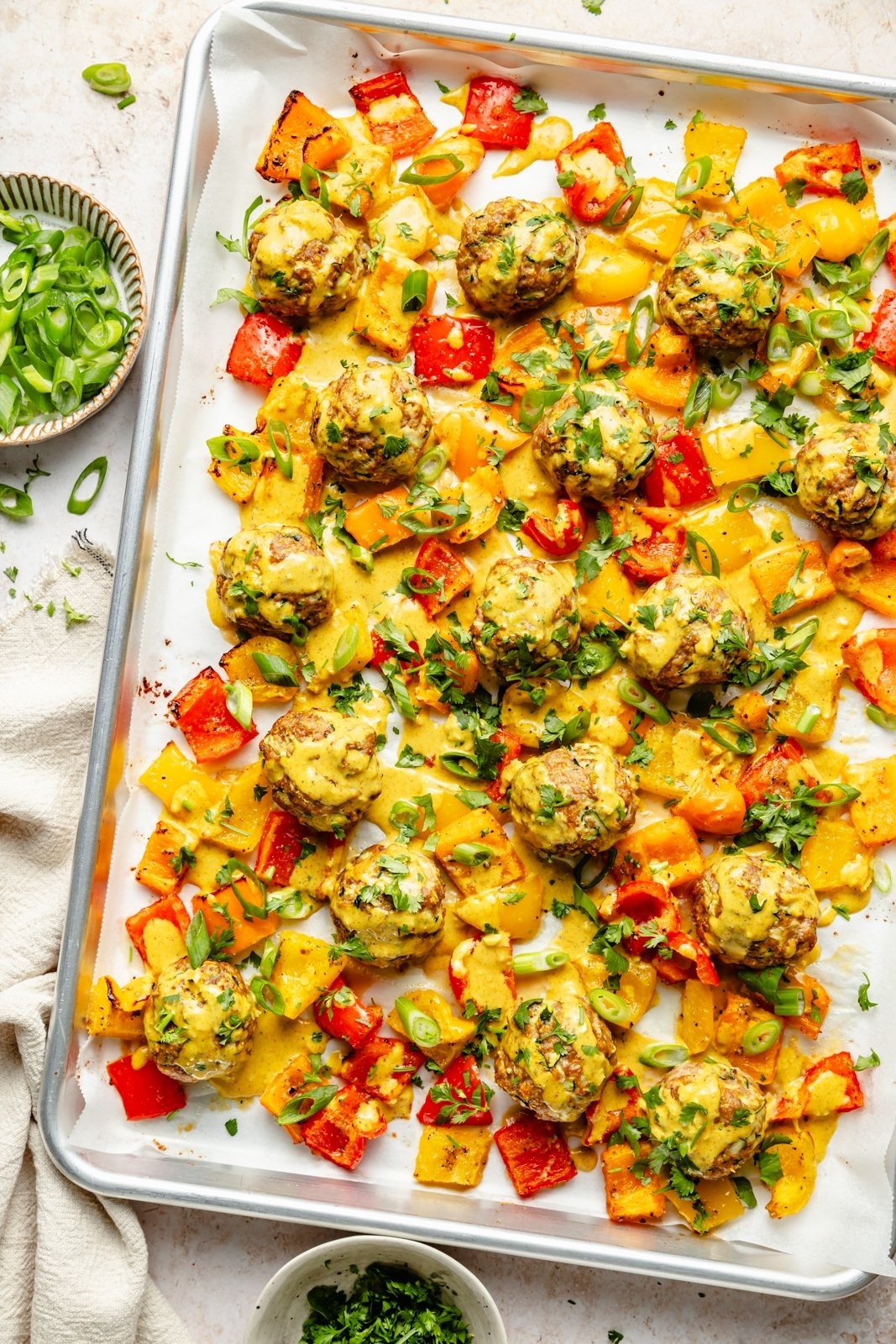 zucchini chicken meatballs with vegetables and curry sauce on a sheet pan