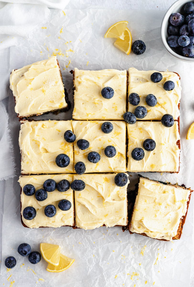 healthy lemon blueberry zucchini cake cut into nine slices topped with frosting