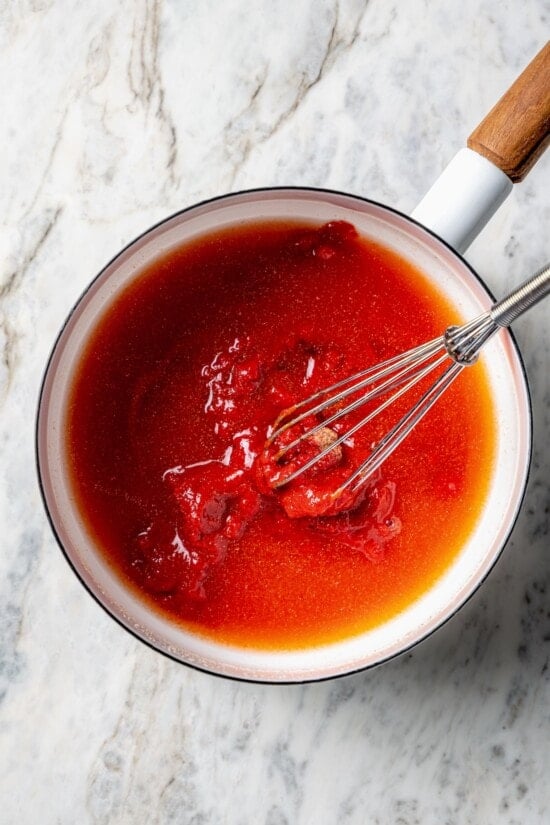 Overhead view of ingredients for homemade ketchup in saucepan with whisk